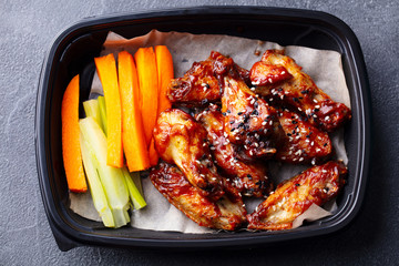 Wall Mural - Chicken wings with vegetable sticks in box. Grey background. Close up. Top view.