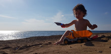 A Little Boy Playing With Toy Truck On The Beach