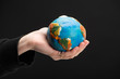 © LIGHTFIELD STUDIOS - Cropped view of plasticine globe in female hand isolated on black, global warming concept