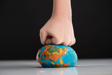 partial view of woman compressing plasticine globe by fist isolated on black, global warming concept