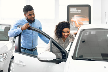 Husband And Wife Choosing New Auto In Car Dealership Store