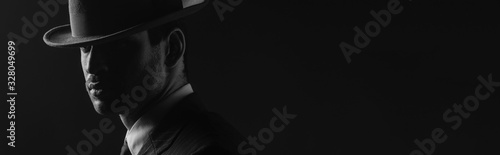 Cuadros en Lienzo Monochrome image of mafioso with felt hat isolated on black, panoramic shot