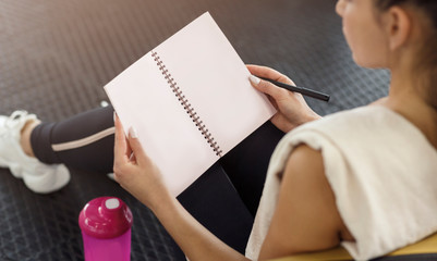 Wall Mural - Unrecognizable woman writing her workout schedule in notebook, closeup