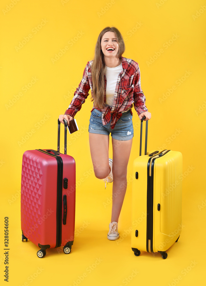 Female tourist with luggage on color background