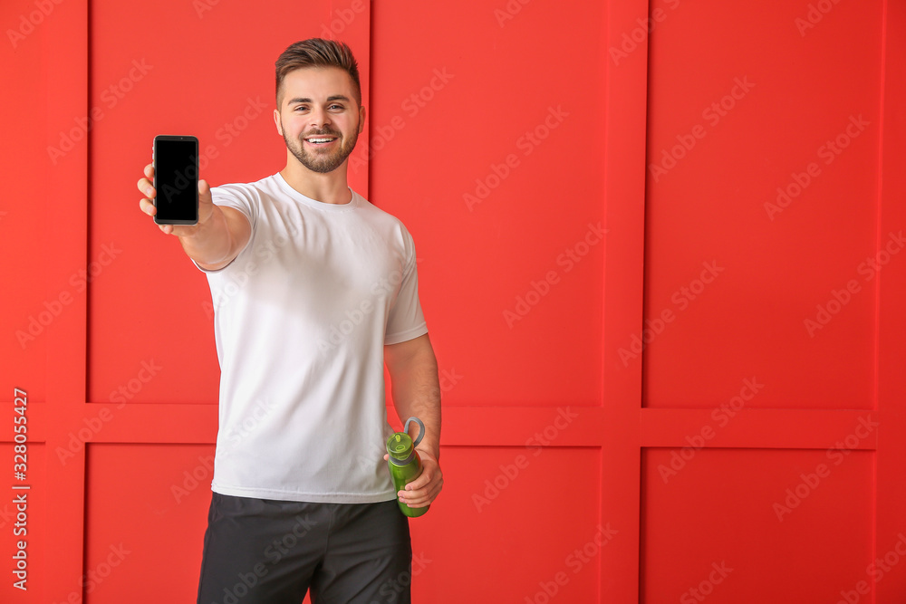Sporty man with mobile phone on color background