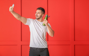 Wall Mural - Sporty man taking selfie on color background