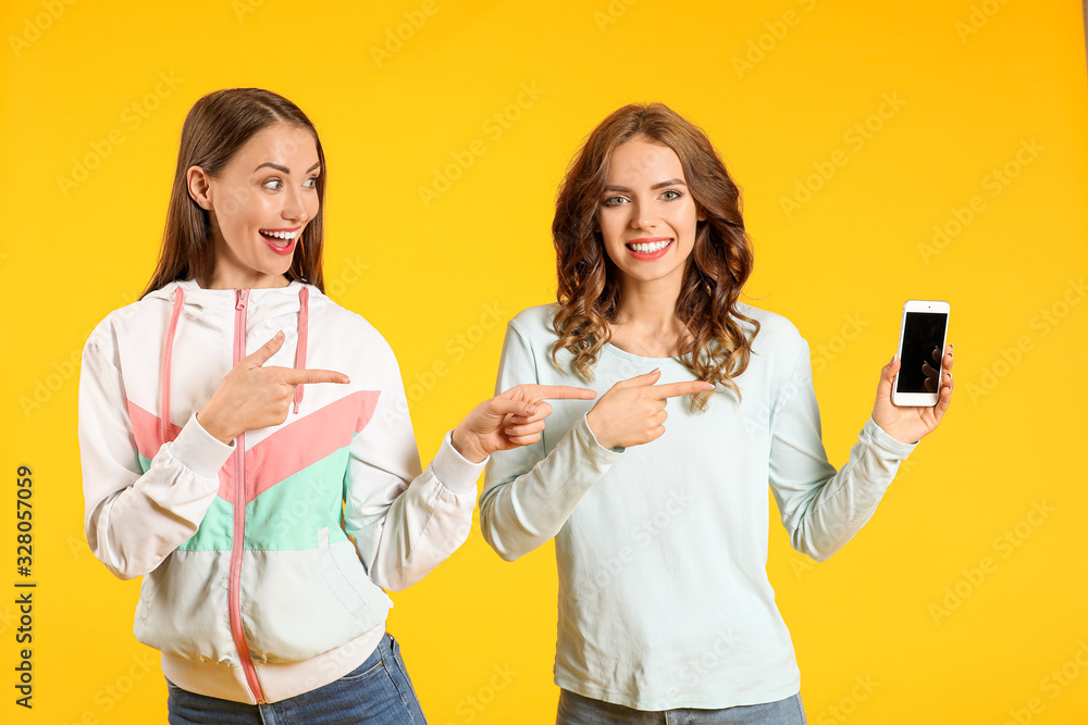 Young women with mobile phone on color background
