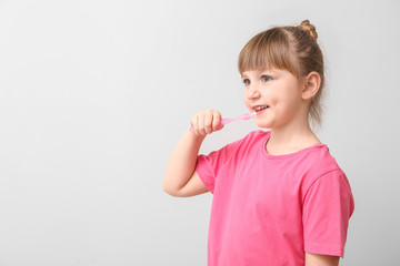 Poster - Little girl with tooth brush on light background