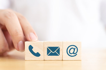 Fototapete - Businessman hand choose wooden block cube symbol icon telephone, envelope email and address sign. Website page contact us or e-mail marketing concept