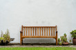 Wooden bench front of a white wall