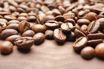 Many coffee beans on wooden background, closeup