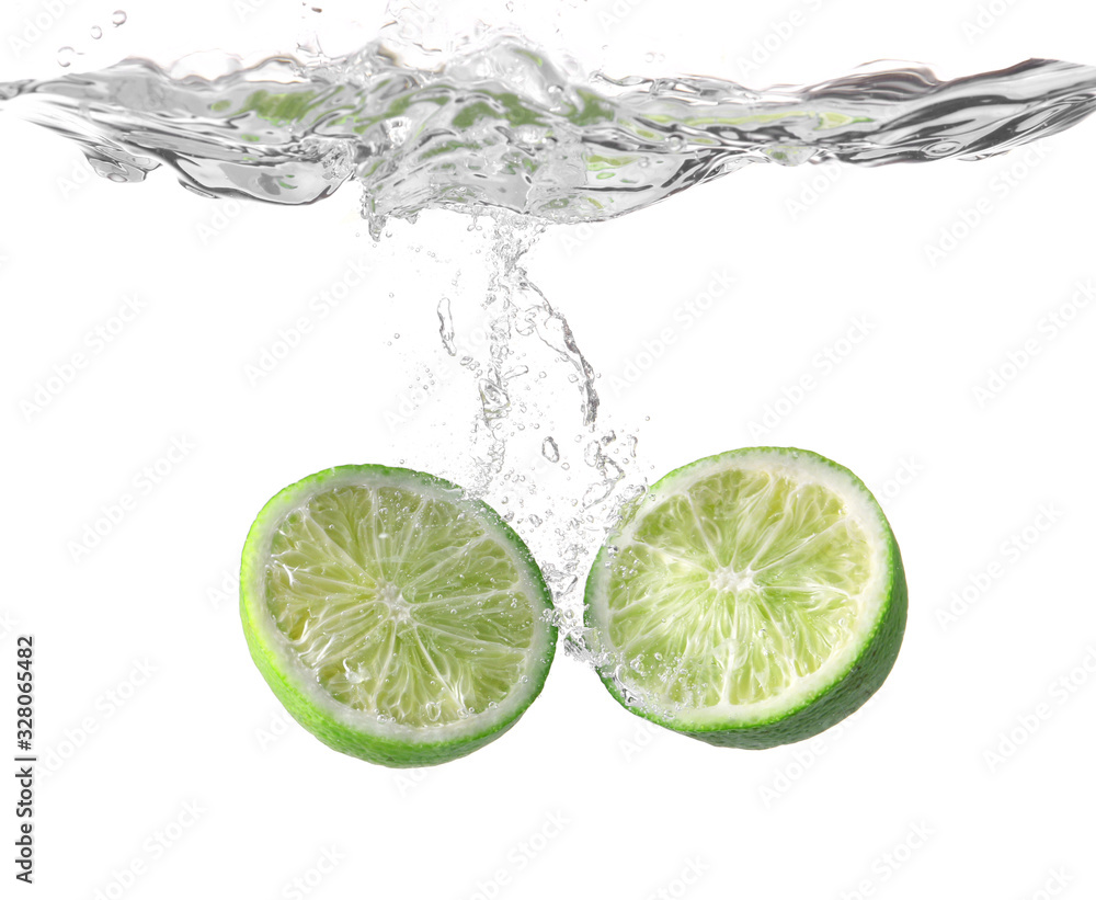 Falling of fresh cut lime into water against white background