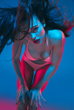 Attractive Brunette Model On Blue Studio Background In Neon Light. Beautiful Women In Underwear Posing With Flying Hair And Dark Make Up. Concept Of Sensuality, Style, Fashion Industry, Characters.