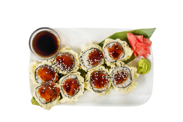 Sushi, rolls, uramaki, tempura with teriyaki sauce, sesame, raw seafood, soy sauce, marinated ginger and wasabi. Food on a banana leaf, on plate, white isolated background, view from above