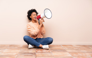 African american woman sitting on the floor shouting through a megaphone