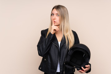 Poster - Young blonde woman with a motorcycle helmet over isolated background doing silence gesture