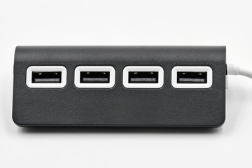 Black portable USB hub for four connections on a white background. Bus povered. Closeup, selective focus