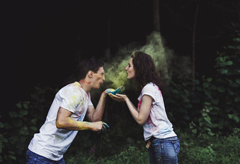 Young cheerful woman and man having fun at Holi paint party