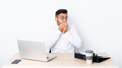 Wall Mural - Young businessman in a workplace covering mouth and looking to the side