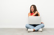 © luismolinero - Young woman with a laptop sitting on the floor celebrating a victory