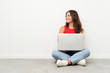 © luismolinero - Young woman with a laptop sitting on the floor looking to the side