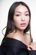 Portrait of a young beautiful Asian girl looking directly at the camera, shoulders open, hands pressed to her chest. The concept of skin care facial, makeup       