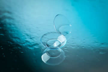 Wall Mural - Contact lenses on mirror surface with water, close up