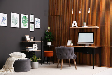 Poster - Comfortable workplace with computer near wooden wall in stylish room interior. Home office design