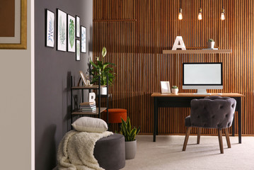 Poster - Comfortable workplace with computer near wooden wall in stylish room interior. Home office design