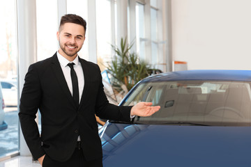 Wall Mural - Young salesman near new car in dealership