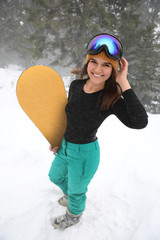 Wall Mural - Young woman with snowboard wearing winter sport clothes outdoors