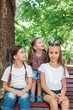 © Elena Kratovich - Three sisters smiling and hugging outdoors in summer park.