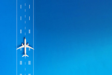 The passenger plane on airport runway and blue background with empty space for text. Top view, copy space