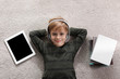© New Africa - Cute little boy with headphones and tablet listening to audiobook on floor indoors, flat lay