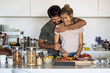 © PhotoAlto - Smiling young woman chopping vegetable while his husband embracing her in kitchen