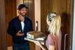 © PhotoAlto - Young woman talking with delivery man while receiving parcels at door