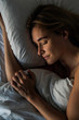 © PhotoAlto - Overhead view of young woman sleeping peacefully on bed in bedroom