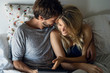 © PhotoAlto - Elevated view of young couple laughing while watching movie on digital tablet in bedroom