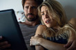 © PhotoAlto - Young couple watching horror movie on digital tablet in bedroom