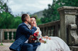  A couple of newlyweds posing on the stairs. Happy Newlywed woman and man embracing and kissing. groom with boutonniere. Beautiful wedding bouquet. Wedding day. Sincere emotions