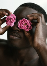 Portrait Of Handsome African Guy Who's Holding Two Roses Near His Face