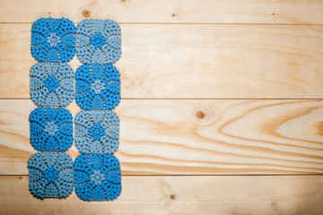 Crocheted cotton napkin with delicate ornament on background of light wooden table with place for text, copy space. Knitting and needlework. Concept of self-development