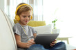 © New Africa - Cute little boy with headphones and tablet listening to audiobook at home
