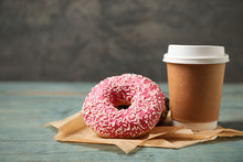 Yummy Donuts With Sprinkles And Paper Cup On Wooden Table