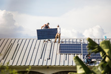 Team Of Electricians Work To Install Solar Panels On Rooftop.