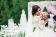 Wedding bouquet in bride's hands. Sincere emotions. Bride against the background of the scenery of the exit ceremony. Wedding day. Happy Newlywed woman