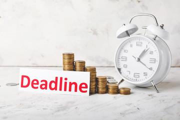 Money, alarm clock and paper with text DEADLINE on table