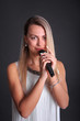 © MaksimM - Portrait of a girl with a microphone in a photo studio on a black background