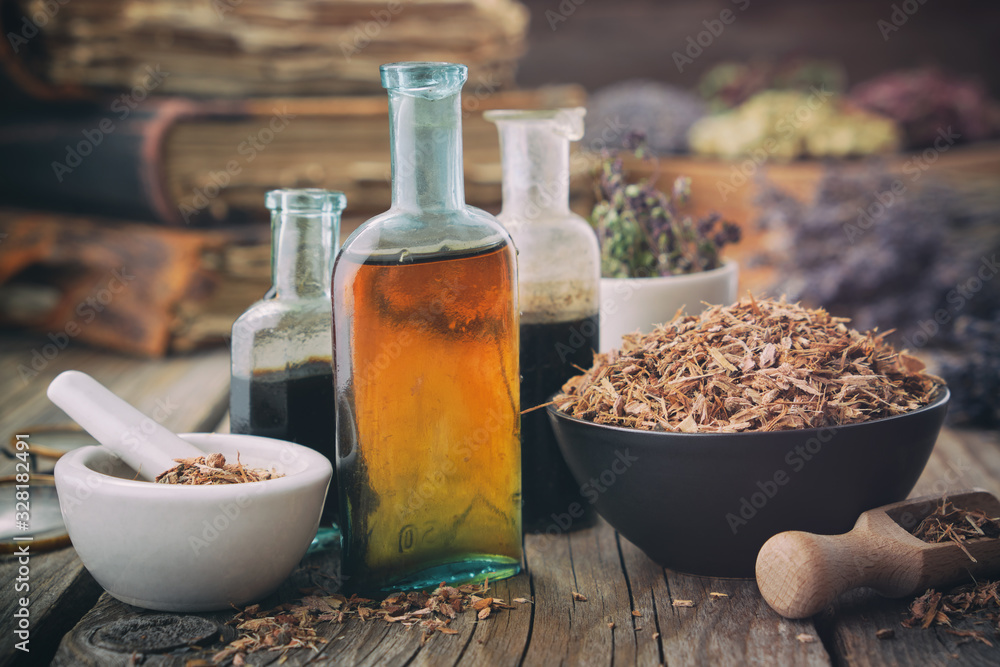 Healthy oak bark in bowl, infusion or tincture bottles. Mortar and bowls of medicinal herbs and books on background. Herbal medicine. - obrazy, fototapety, plakaty 