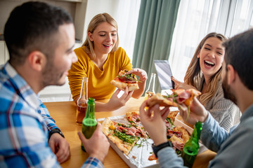 Group of cheerful friends eating delicious pizza at home